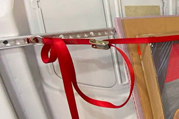 Red cam buckle L-track tie-down strap in use