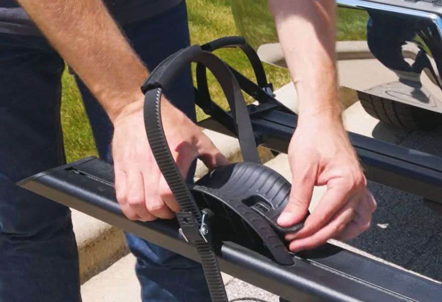 Man adjusts tire cradle on empty bike carrier