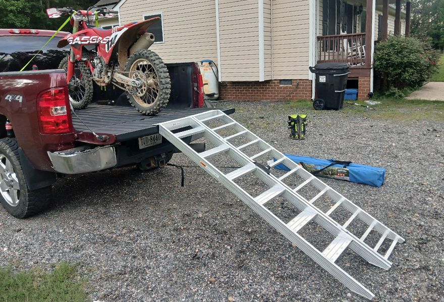 dirt bike in pickup truck bed outside a house