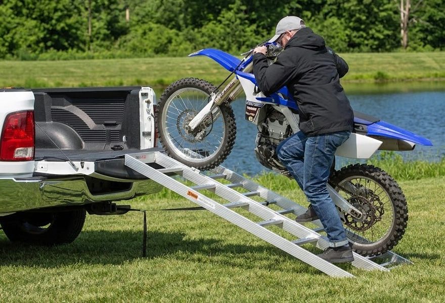 man walking dirt bike into truck bed with Black Widow ramp