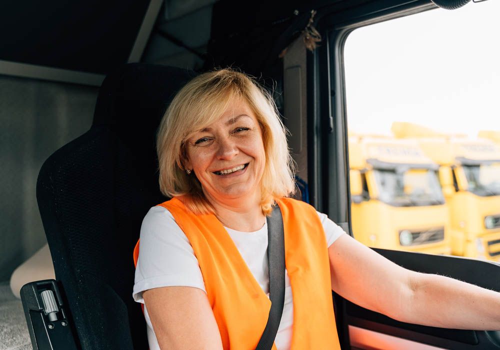 truck driver drinking coffee next to his truck while looking at a clipboard