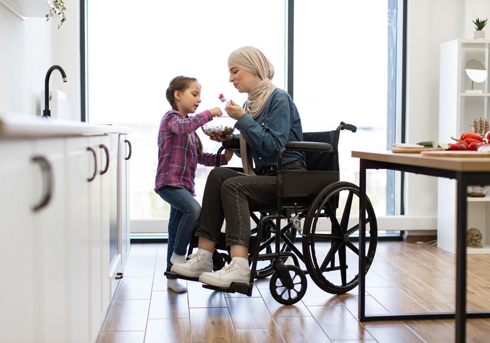 Daughter and mother in a wheelchair enjoying a moment in the kitchen together