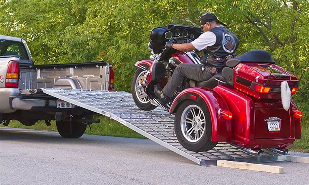 man riding a trike up a loading ramp into a pickup truck bed
