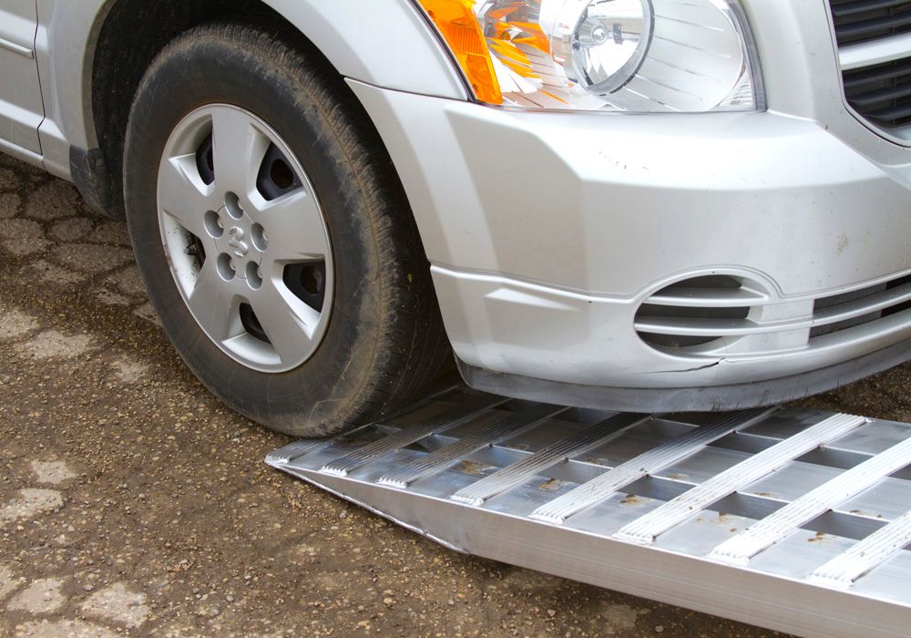 minivan driving up an aluminum loading ramp