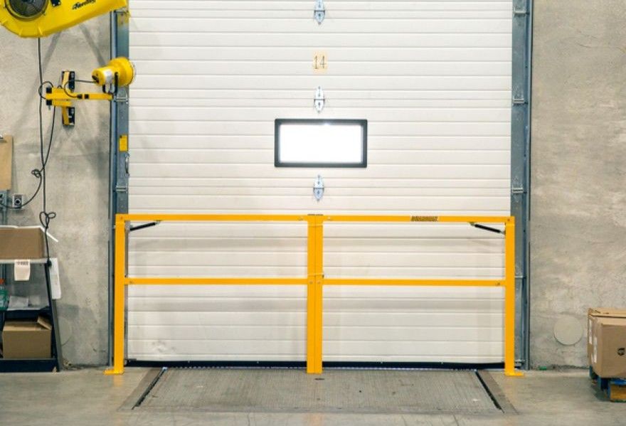 Yellow dock safety gate folded down across a loading dock opening
