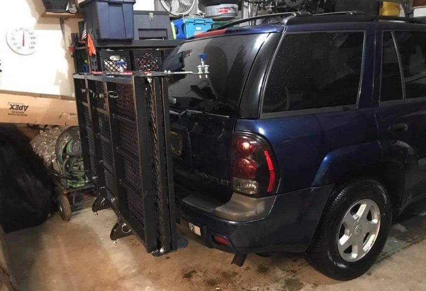 Hitch cargo carrier folded upright against vehicle