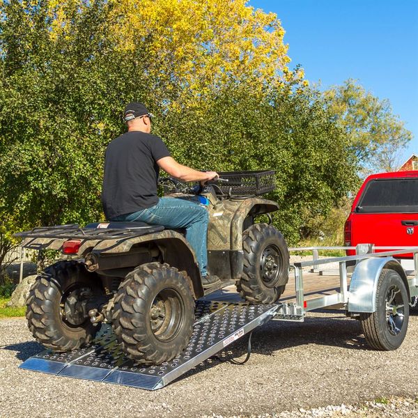 man loading up an ATV onto a single ATV trailer with aluminum loading ramps